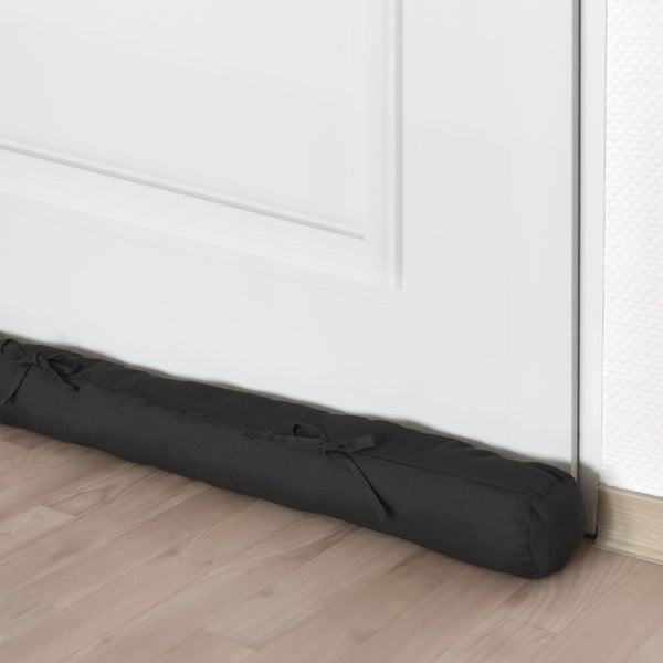 Textil Zugluftstopper vor einer Tür auf Holzboden