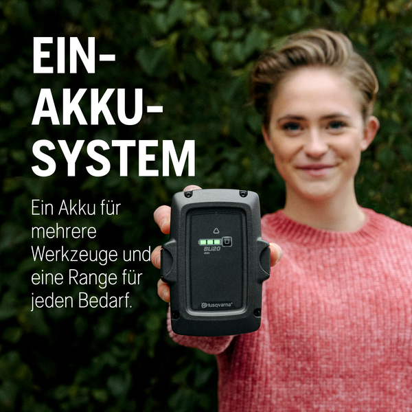 Frau hält Husqvarna Akku BLi20 4Ah in die Kamera
