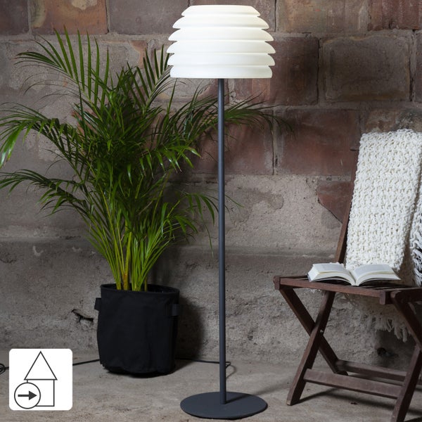 Stehlampe neben Zimmerpflanze und Klappstuhl mit Buch