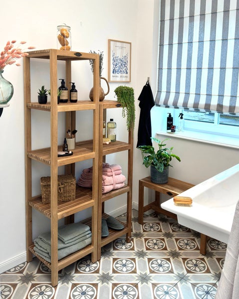 Badezimmer mit Holzregalen, Handtüchern und Dekorationen auf gemusterten Fliesen