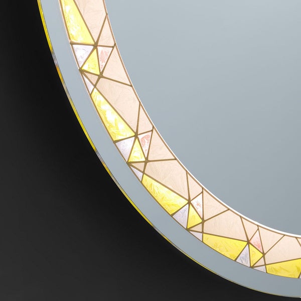 Detail eines runden Wandspiegels mit einem dekorativen Rand aus geometrischen Dreiecken und kristalliner Textur.