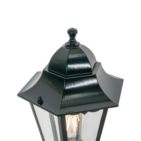 Schwarze Außenleuchte im Laternen-Design mit Glaseinsätzen und sichtbarem Filament-Leuchtmittel.