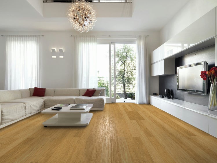 Modernes helles Wohnzimmer mit hellem Bambusparkett, großer weißer Couch, Couchtisch und einer TV-Wand vor großen Fenstern.