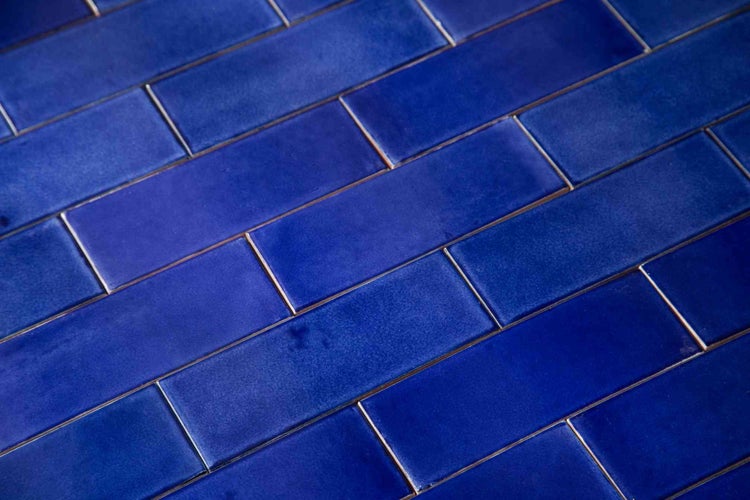 Blaue, rechteckige Wandfliesen im Metro-Stil mit glänzend glasierter Oberfläche in versetztem Verlegemuster.