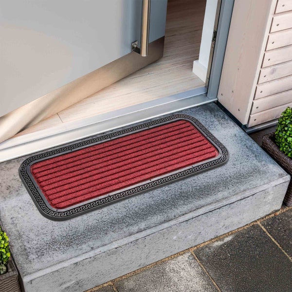 Fußabtreter mit Mäandermuster vor einer geöffneten Tür