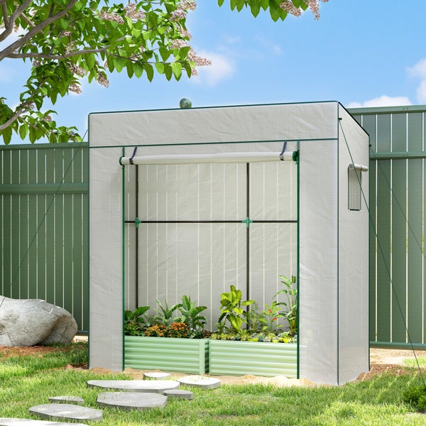 Foliengewächshaus mit aufgerolltem Eingang und zwei grünen Hochbeeten voller Pflanzen in einem hellen Garten.