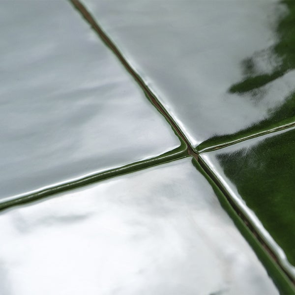 Nahaufnahme von quadratischen Wandfliesen mit glänzender Oberfläche und unebener Struktur.