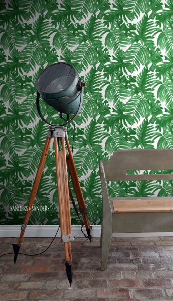 Stehlampe mit Stativ vor einer Wand mit Blättermuster