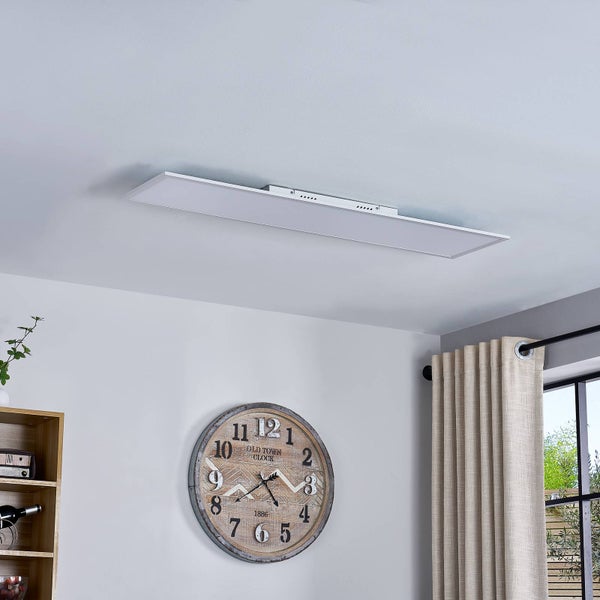 Flaches, rechteckiges LED-Panel an der Decke montiert in einem hellen Raum mit Wanduhr und Vorhängen.