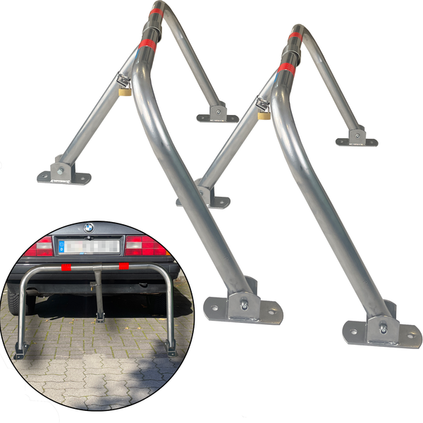 Zwei silberne Parkbügel mit roter Markierung und Vorhängeschloss als Diebstahlschutz für Parkplätze.