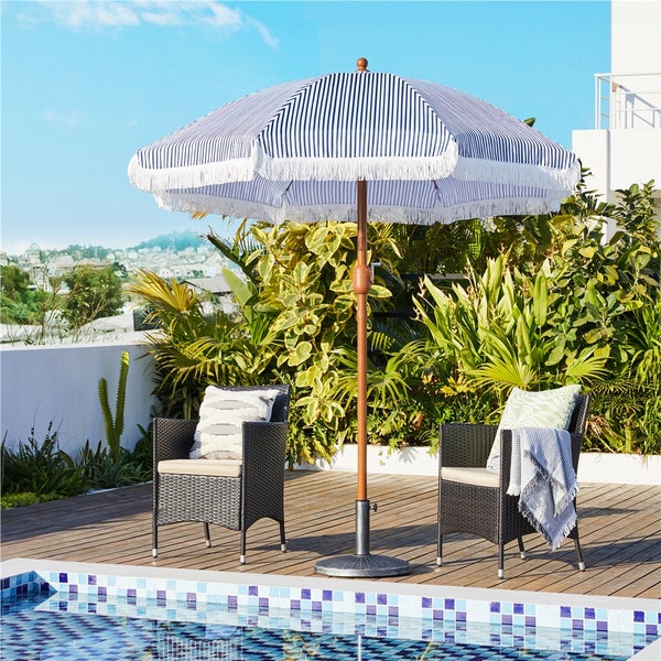 Gartenszene mit gestreiftem Sonnenschirm, zwei Rattansesseln und Pool