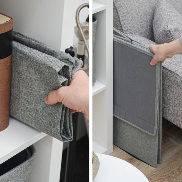 Eine Hand verstaut eine zusammengefaltete Aufbewahrungsbox aus Stoff platzsparend in einem Regal und in einer schmalen Nische neben einem Sofa.