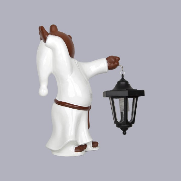 Gartenfigur Bär im weißen Nachthemd mit schwarzer Solar-Laterne.