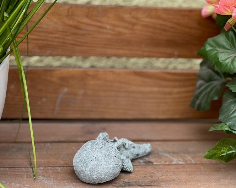 Kleine Gartenfigur aus Steinguss in Form eines schlüpfenden Drachenbabys aus einem Ei.