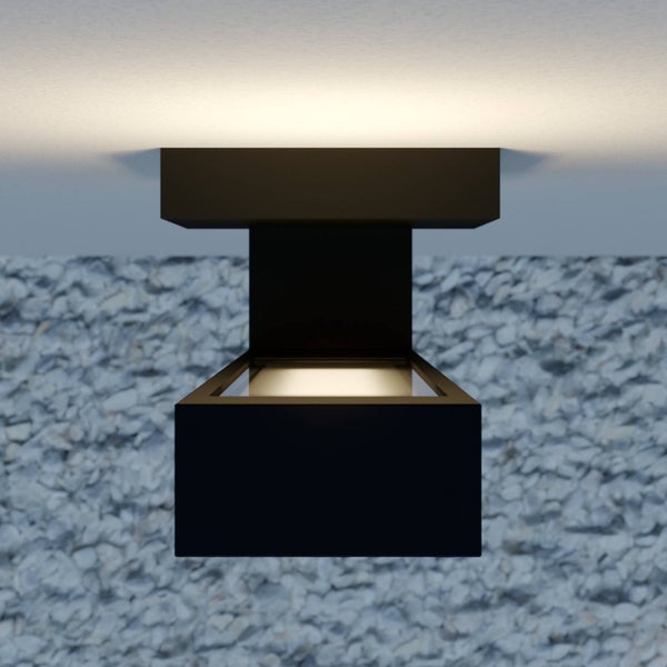 Schwarze LED Außenwandleuchte mit Lichtaustritt nach oben und unten an einer Wand über Kieselsteinen.