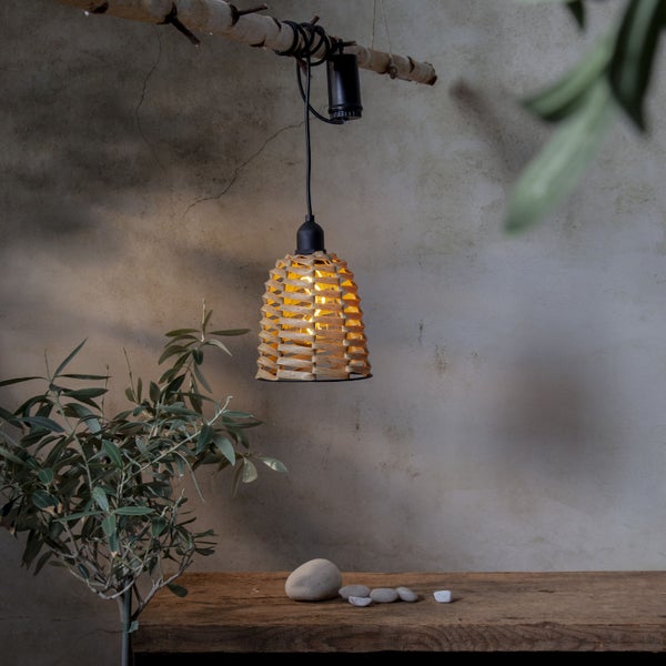 Dekorative Pendelleuchte aus Holz über einem Holztisch mit Steinen und einer Pflanze
