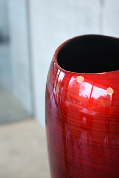 Hochglänzende rote Blumenvase mit Holzstruktur und dunkler Innenseite.