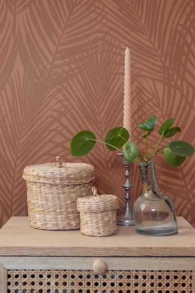 Dekorative Szene mit Aufbewahrungskörben, Kerzenständer, Kerze und Pflanze auf einem Schrank