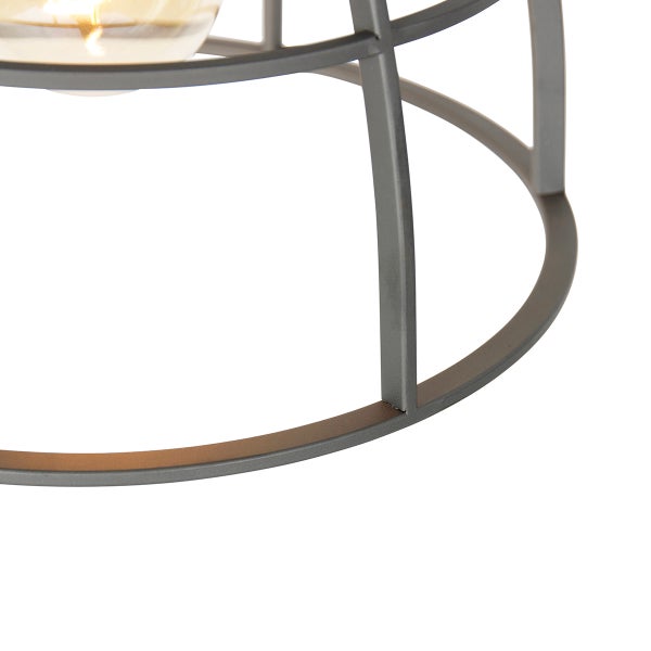Detailansicht einer runden Metallleuchte mit Glühlampe im Gitterdesign.