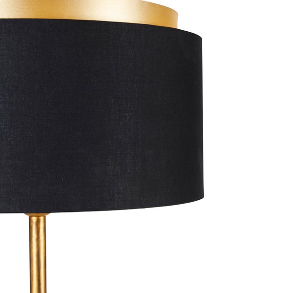 Detail einer Stehlampe mit schwarzem Lampenschirm und goldenem Lampenfuß