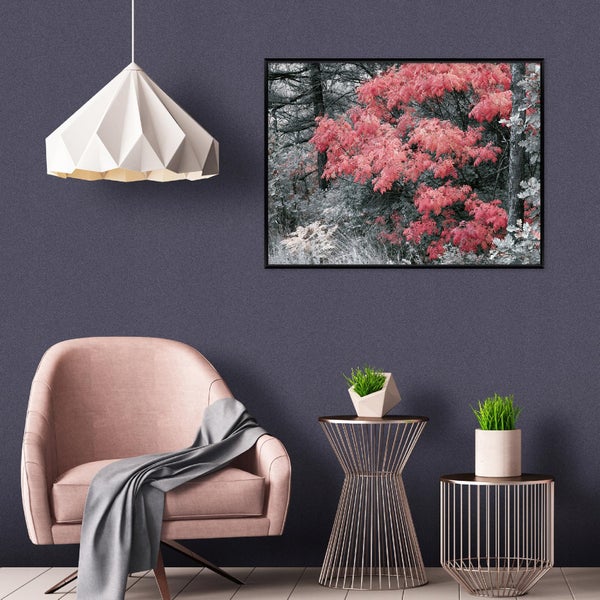 Wohnzimmer mit Sessel, Beistelltischen, geometrischer Lampe und einem gerahmten Wandbild mit einer Waldlandschaft in herbstlichen Farben.