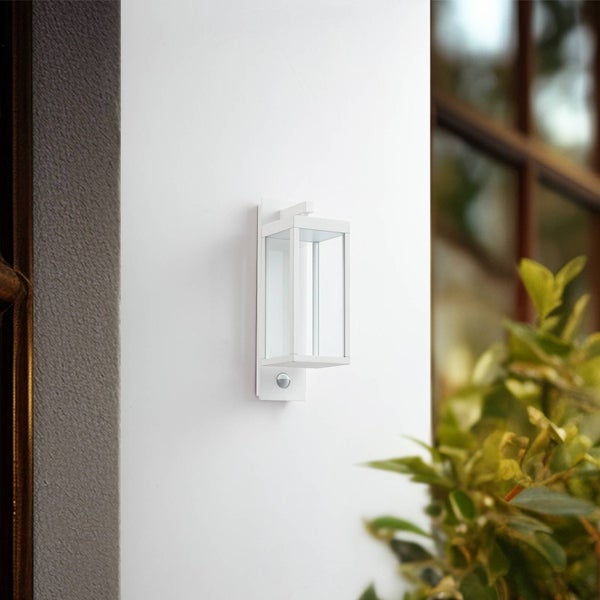 Moderne weiße Außenwandleuchte mit Bewegungsmelder, rechteckiges Design mit Glaseinsätzen, an einer Hauswand montiert.