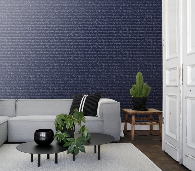 Wohnraum mit Sofa, Tisch und Wandtapete mit Schriftmuster