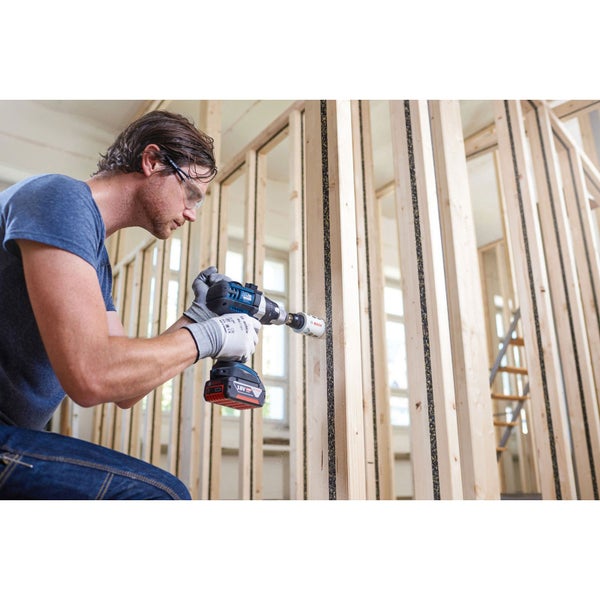 Ein Handwerker bohrt mit einer Akku-Bohrmaschine ein Loch in eine Holzwand.