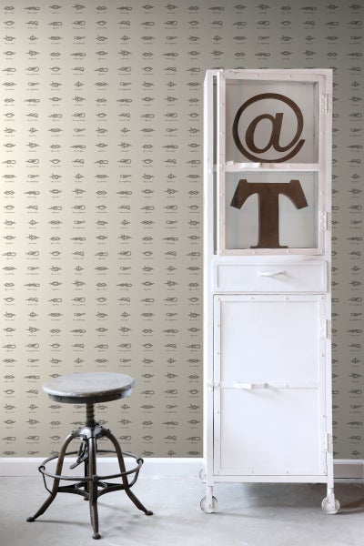 Szene mit einem Hocker, einem Schrank mit Dekoration und einer Tapete mit Knotenmotiven