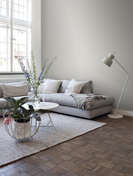 Helles Wohnzimmer mit Sofa, Teppich, Tisch, Stehlampe und Zimmerpflanze