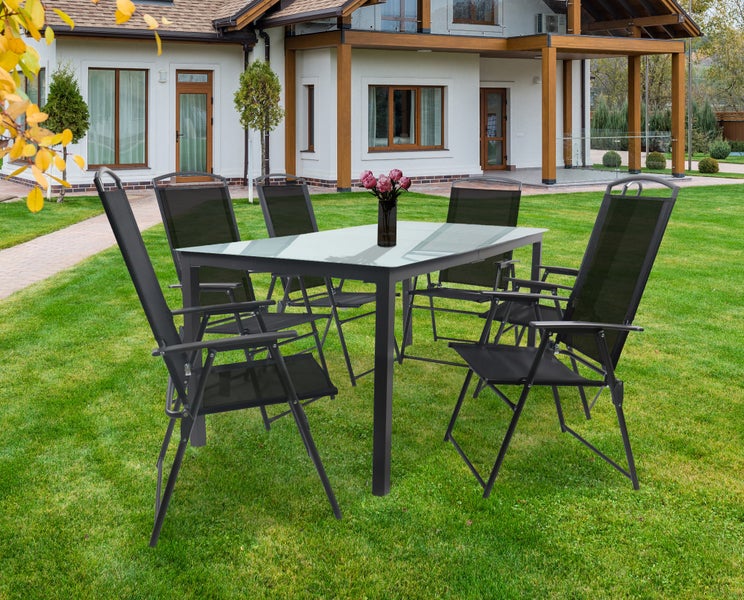 Gartensitzgruppe mit Tisch und sechs Stühlen auf einer Rasenfläche vor einem Haus.