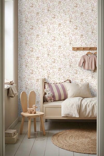 Vliestapete mit Blumen- und Hasenmuster in einem hellen Kinderzimmer mit Holzbett, Hasenstuhl und rundem Juteteppich.