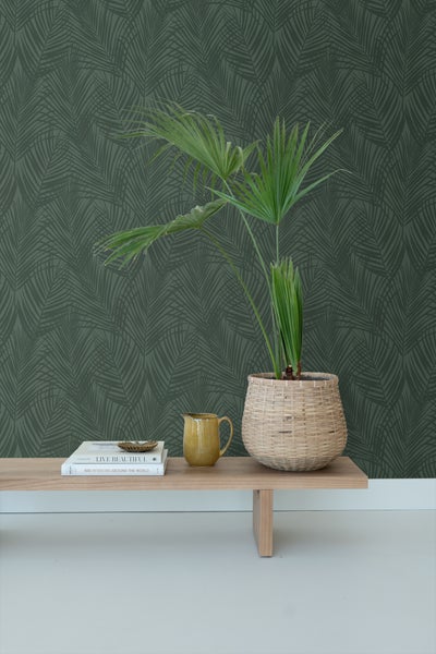 Dekorative Tapete mit Palmenmuster in einem Raum mit Tisch und Topfpflanze.