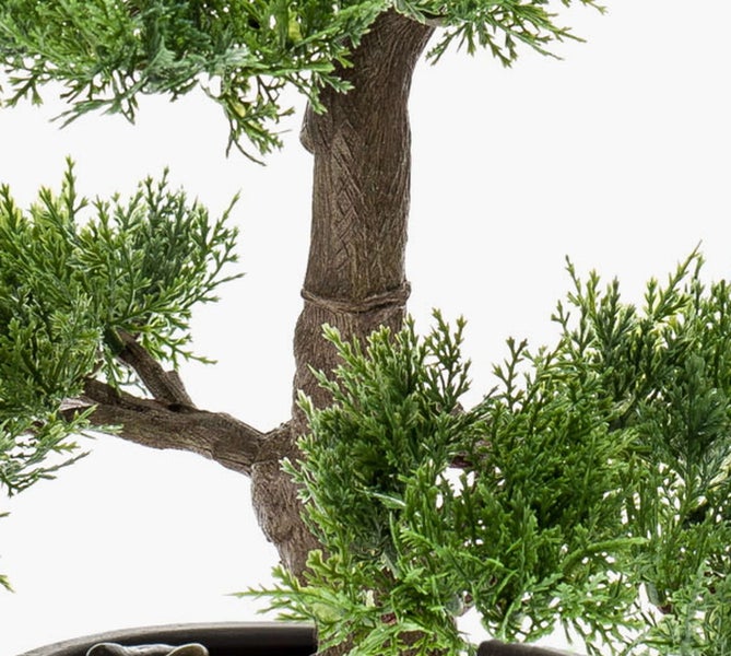 Detailansicht eines künstlichen Bonsais mit braunem Stamm und grünen Nadelzweigen.