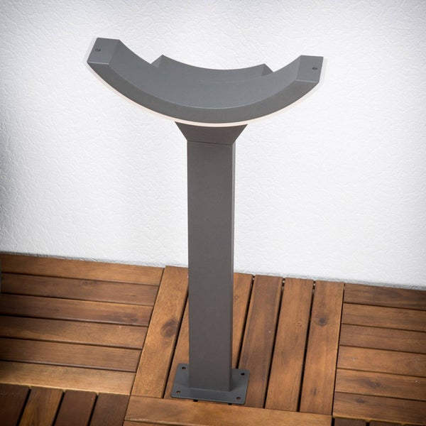 Anthrazitfarbene LED-Außenstehleuchte mit gebogenem Leuchtenkopf, montiert auf Holzfliesen.