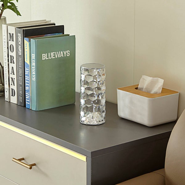 Transparente Glasvase mit Wabenstruktur auf einer Kommode neben Büchern und einer Taschentuchbox.