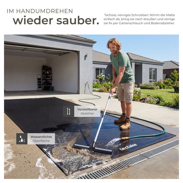 Ein Mann reinigt eine wasserdichte Unterlegmatte mit einem verstellbaren Bodenabzieher und einem Gartenschlauch auf einer Garageneinfahrt.