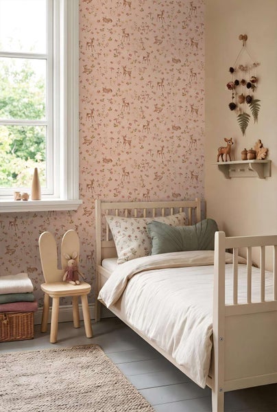 Einrichtung eines Kinderzimmers mit Tapete mit Rehmotiv, einem Holzbett, einem Stuhl in Hasenform und dekorativen Waldaccessoires.