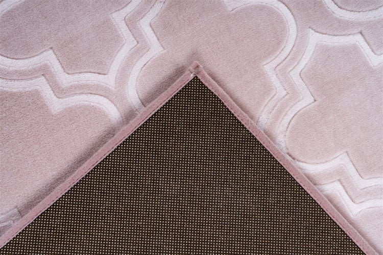 Detailaufnahme eines rosa Teppichs mit geometrischem Reliefmuster und rutschhemmender Rückseite mit kleinen Noppen.