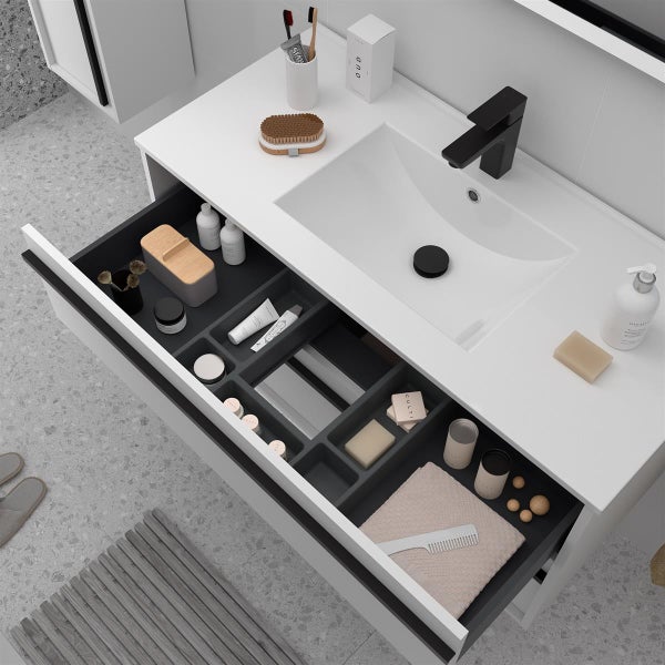 Moderner Waschtischunterschrank in Weiß mit schwarzer Armatur und offener Schublade inklusive Inneneinteilung und Badutensilien.