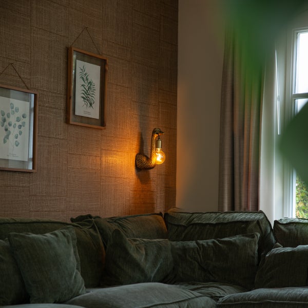 Wohnzimmer mit Wandleuchte in Schwanenhalsform und grüner Couch