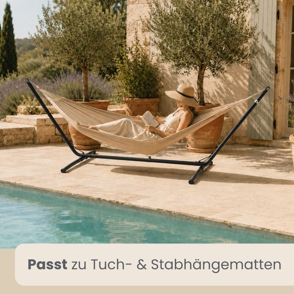 Eine Frau liest in einer hellen Tuchhängematte mit schwarzem Metallgestell am Pool. Passend für Tuch- und Stabhängematten.