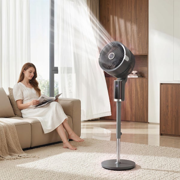 Moderner Standventilator in hellem Wohnzimmer mit Frau auf dem Sofa, verdeutlichte Luftzirkulation.