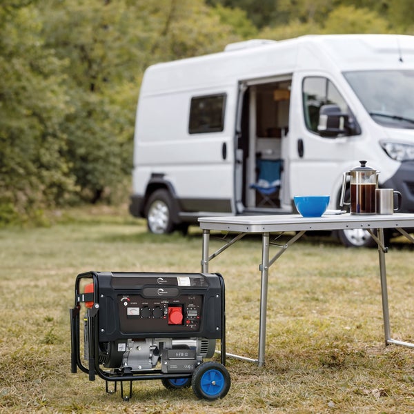 Mobiler Stromerzeuger auf einer Wiese vor einem Wohnmobil mit einem Campingtisch