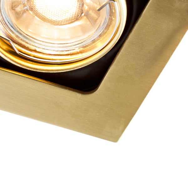 Quadratischer Einbaustrahler aus gebürstetem Metall in Goldoptik mit eingeschalteter Lichtquelle.