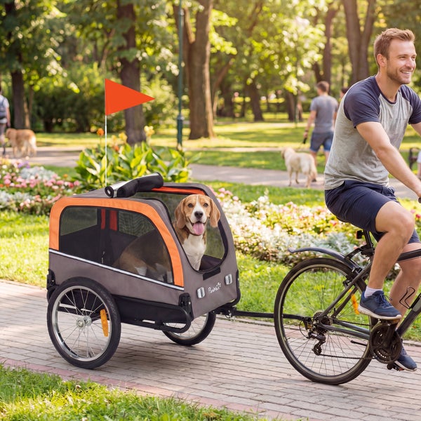 Fahrradanhänger für Hunde von PawHut, angekuppelt an ein Fahrrad in einem sonnigen Park mit einem Hund darin.