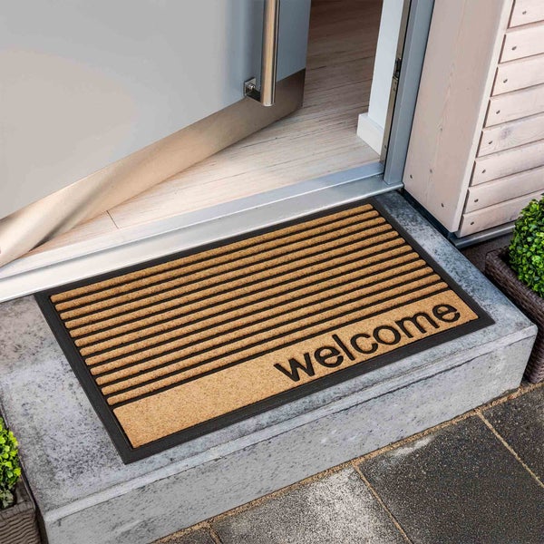 Fußmatte mit Willkommensgruß vor einer Haustür
