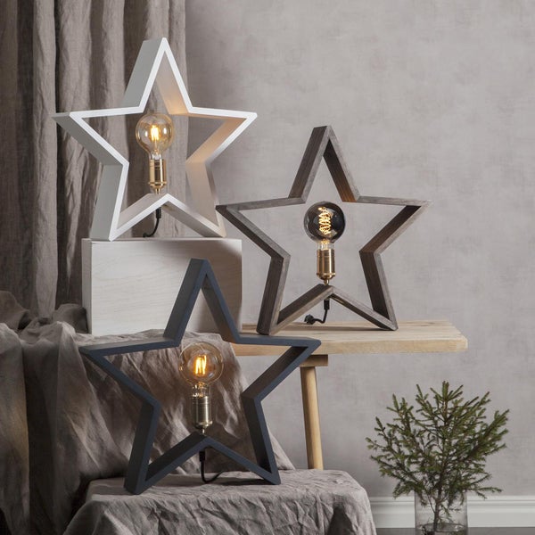Dekorative Sternleuchten aus Holz in verschiedenen Ausführungen auf Tisch und Hocker