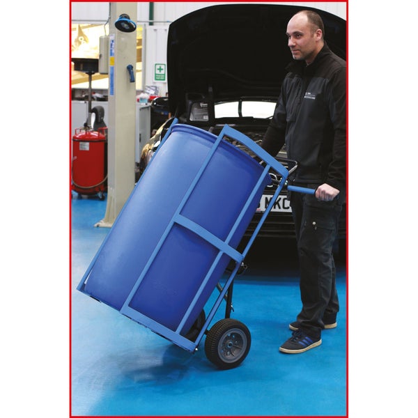 Eine Person schiebt einen blauen Müllcontainerwagen in einer Werkstatt.