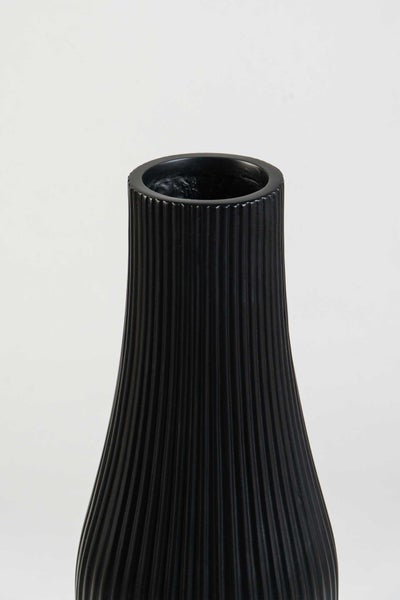Nahaufnahme einer schwarzen Vase mit vertikaler Rippenstruktur aus Steinzeug.